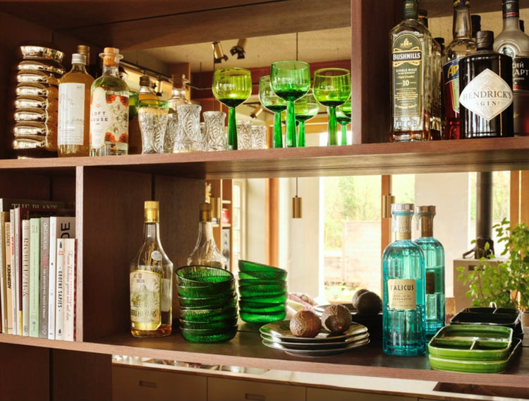 open bar shelves with bottles and green colored high stem wineglasses