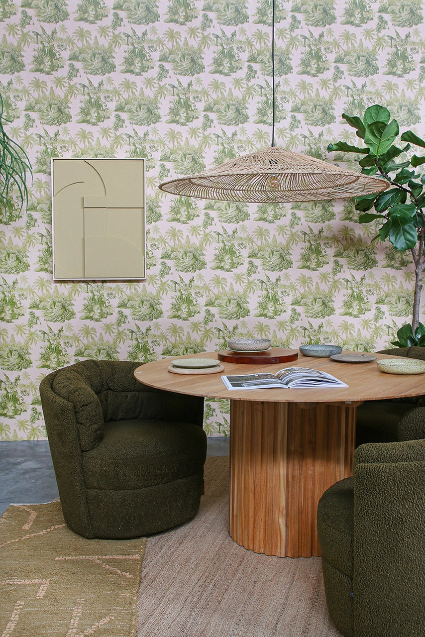 hand woven large triangle shape pendant light above a teak round dining table with green chairs and green wallpaper