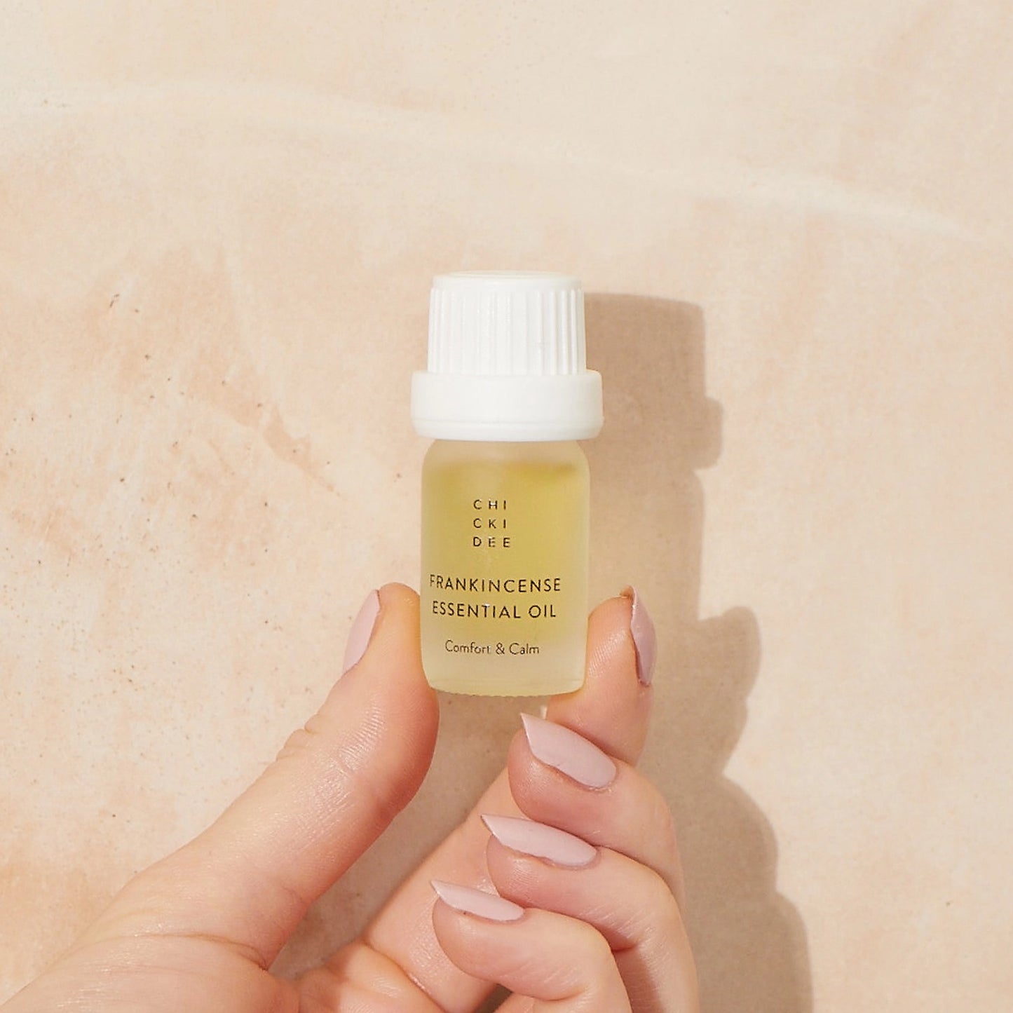 hand holding 5 ml glass bottle with Frankincense essential oil