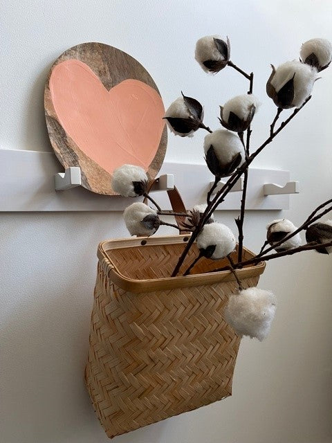 peach colored heart on a natural wooden plate on a rack with a bamboo basket