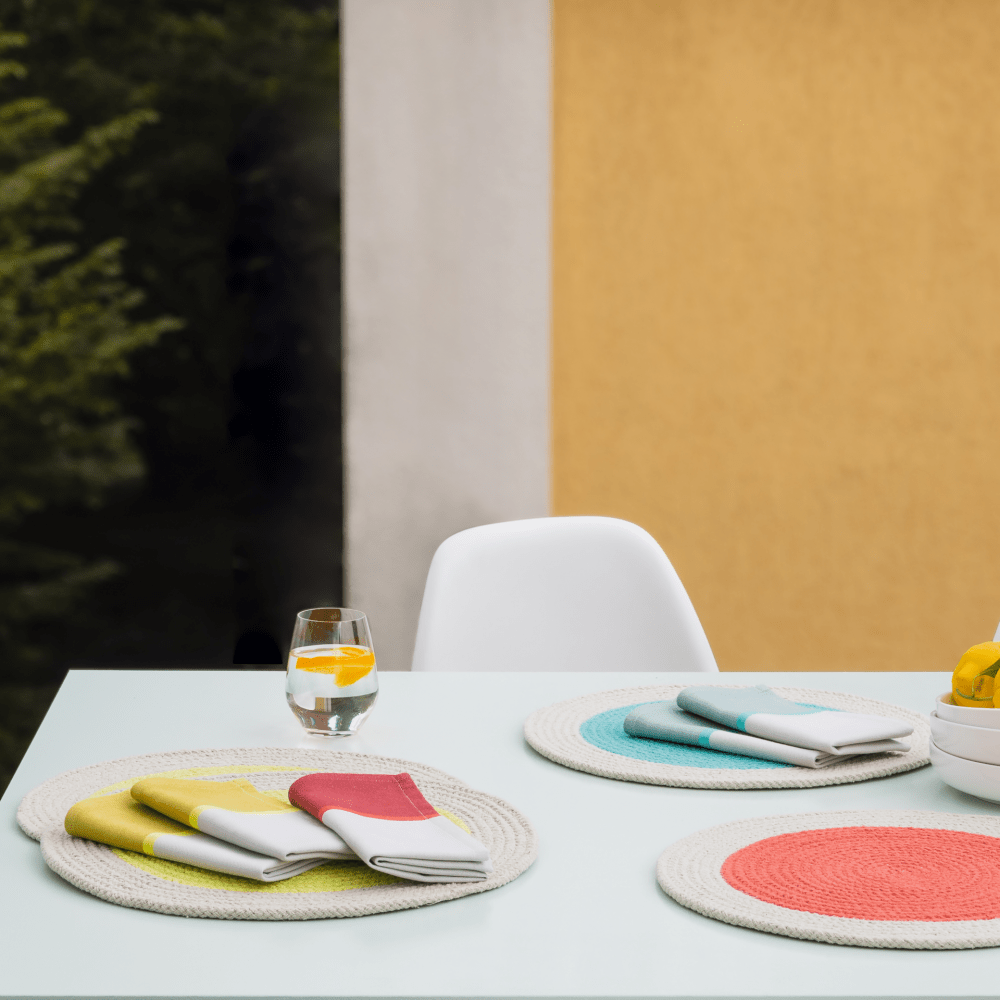 red, yellow and green with beige napkins on table with round placemats