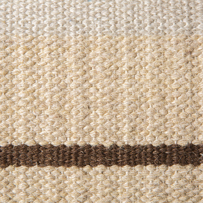detail of  handwoven lumbar shaped woolen pillow with brown stripe and green piping