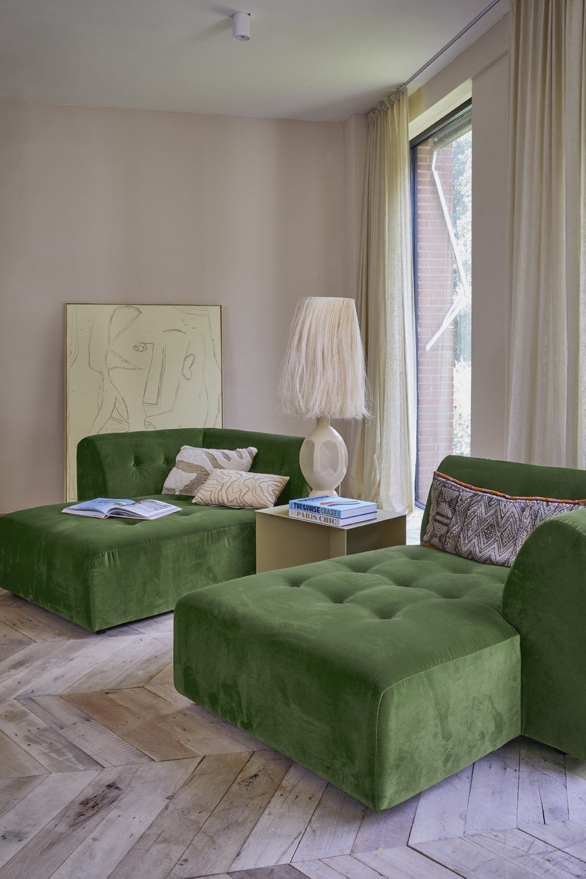 tall sand colored table lamp with stoneware base and abaca fiber shade on a table next to a velvet green divan sofa