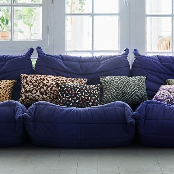 double sided lumbar pillow in brown and green colors with blue trim on a sofa with other pillows