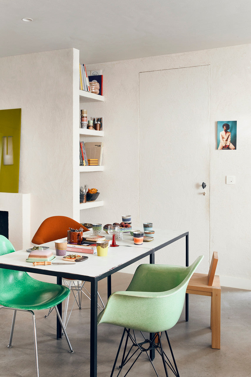 dining table with green tub chair and 70s ceramics as table setting