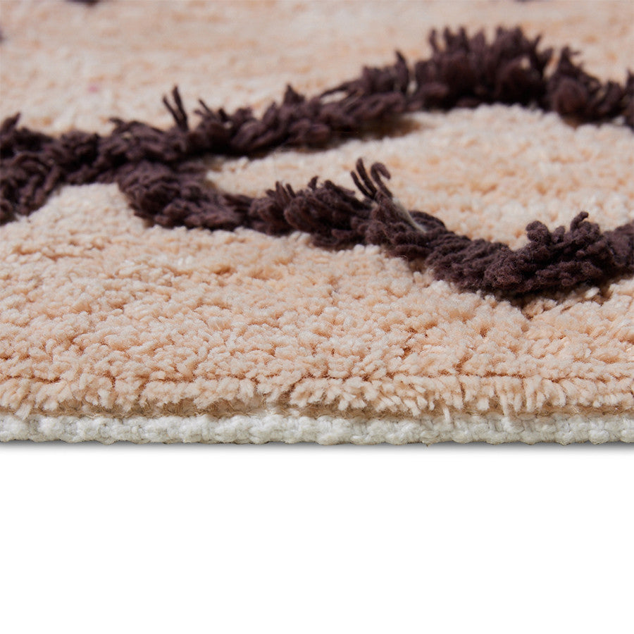 tail of salmon colored bath mat rug with brown and purple design