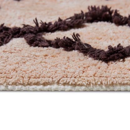 tail of salmon colored bath mat rug with brown and purple design