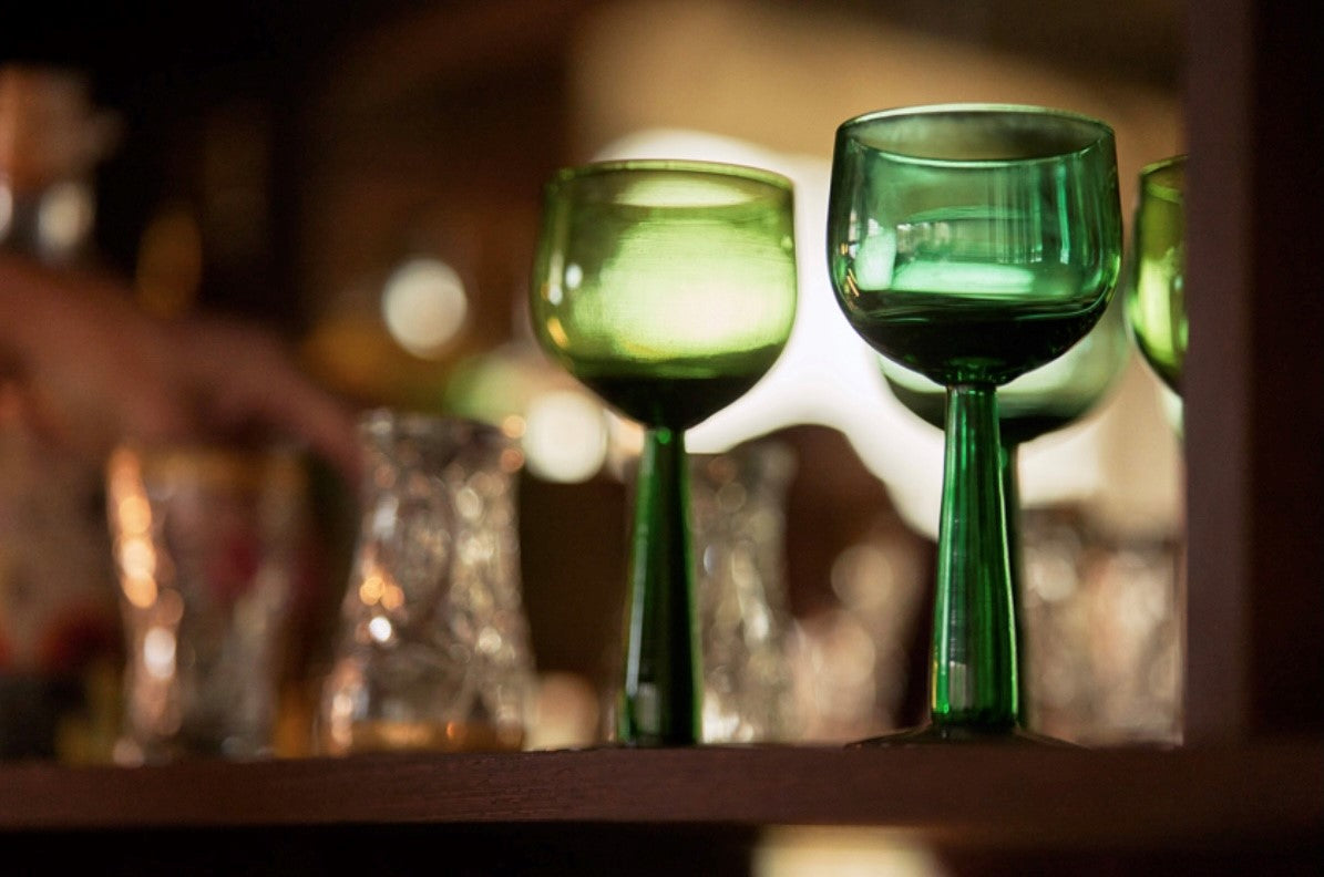 two green colored high stem wineglasses on a shelf