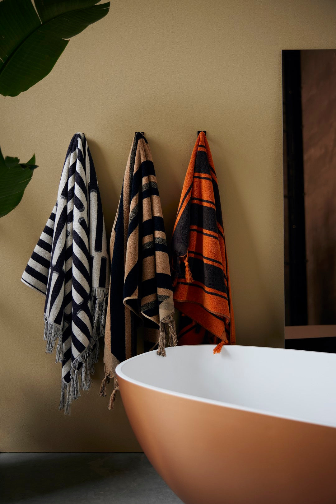 orange and brown striped large bath towel hanging on wall in bathroom 