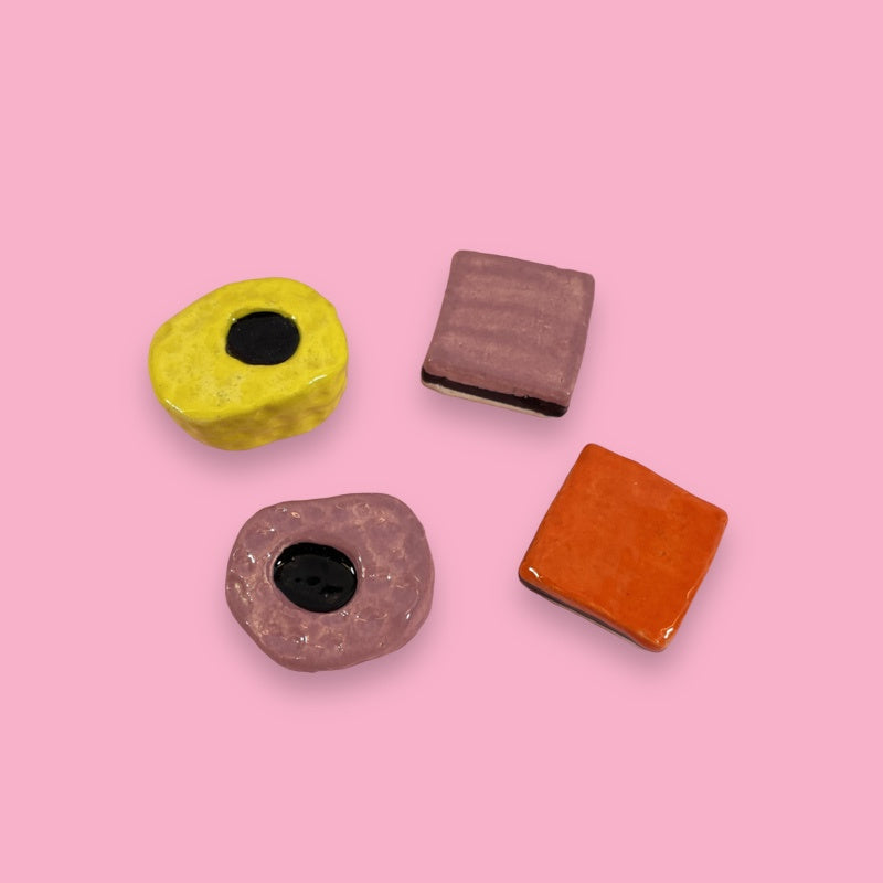 4 pieces of English licorice made from glazed ceramics in yellow, purple orange and black