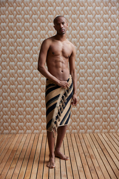 man wearing a brown and black diagonal striped bath towel with fringes
