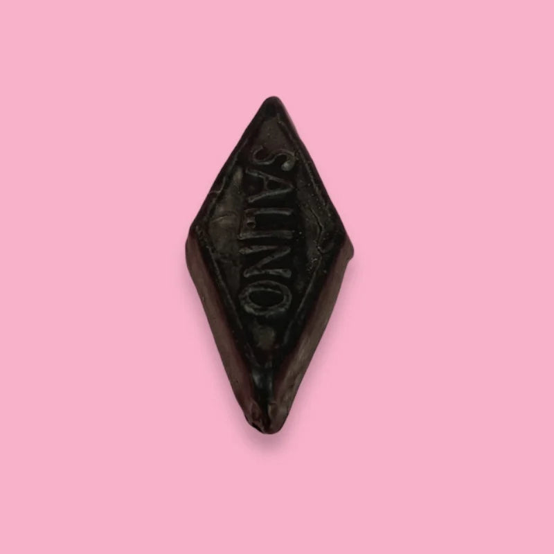 pink background with black triangle shaped piece of Dutch Salino licorice