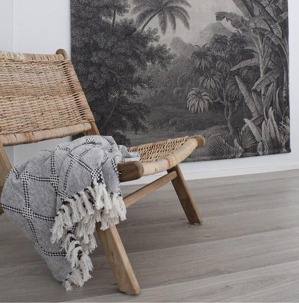 Rattan lounge chair with black white and grey diamond pattern throw blanket