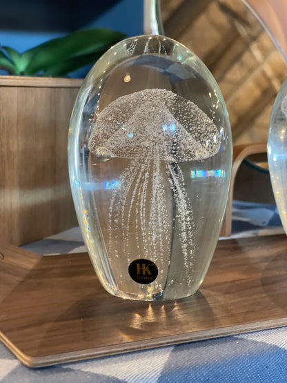 glass object with a white artificial jellyfish on a wooden tray