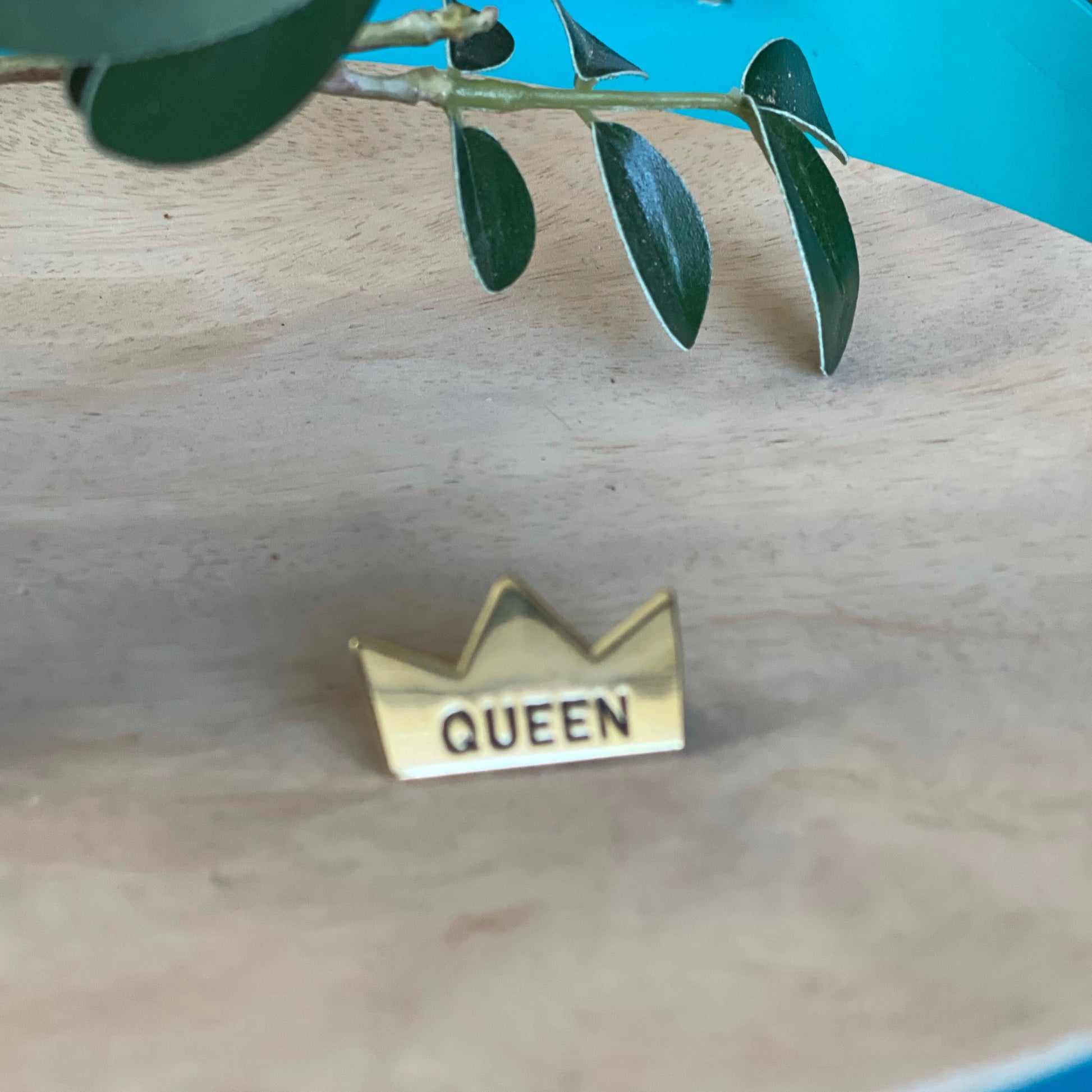 gold enable pin of a crown with queen engraved