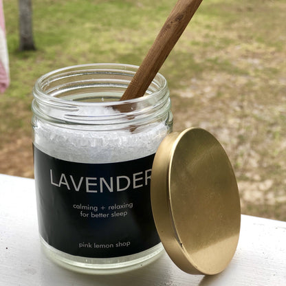 Lavender smelling bath salt in a glass jar with a wooden spoon