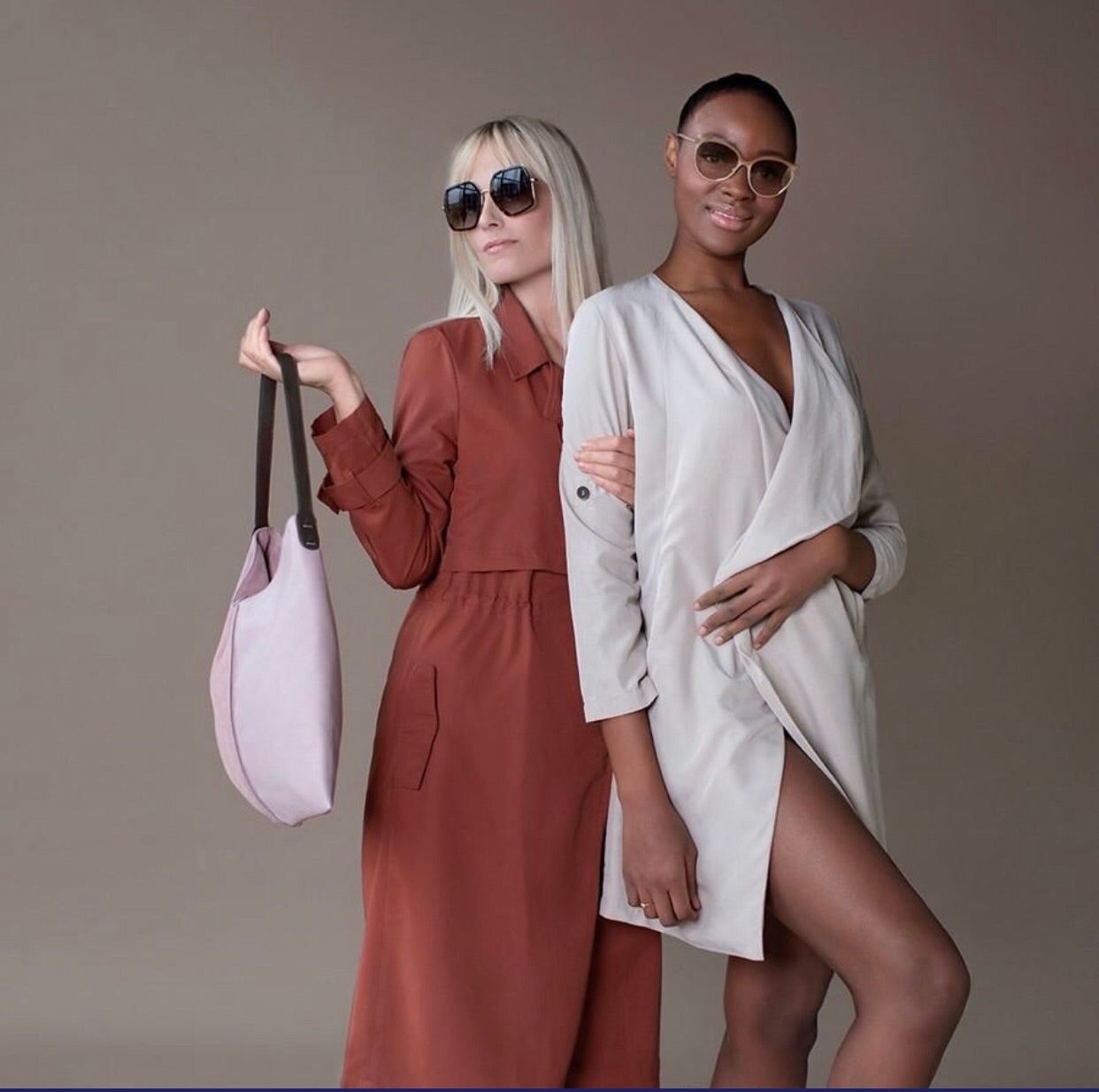 two women one with a pink leather bag and a coral red raincoat and one with a white raincoat 