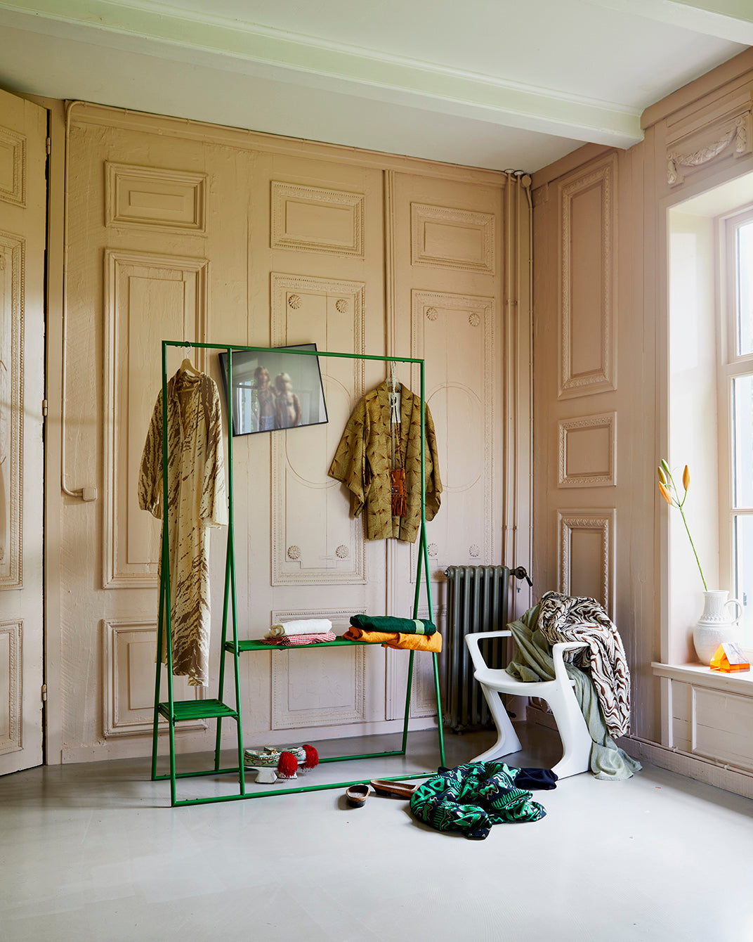 room with paneling and green open wardrobe clothing rack