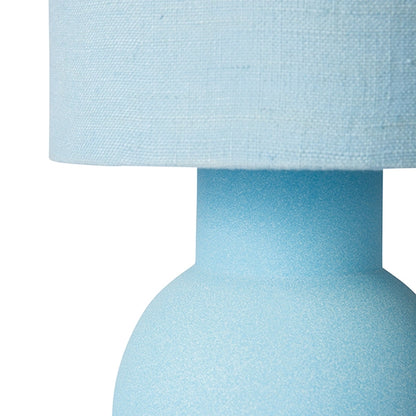 detail of pastel blue table lamp with ball foot and tall linen shade