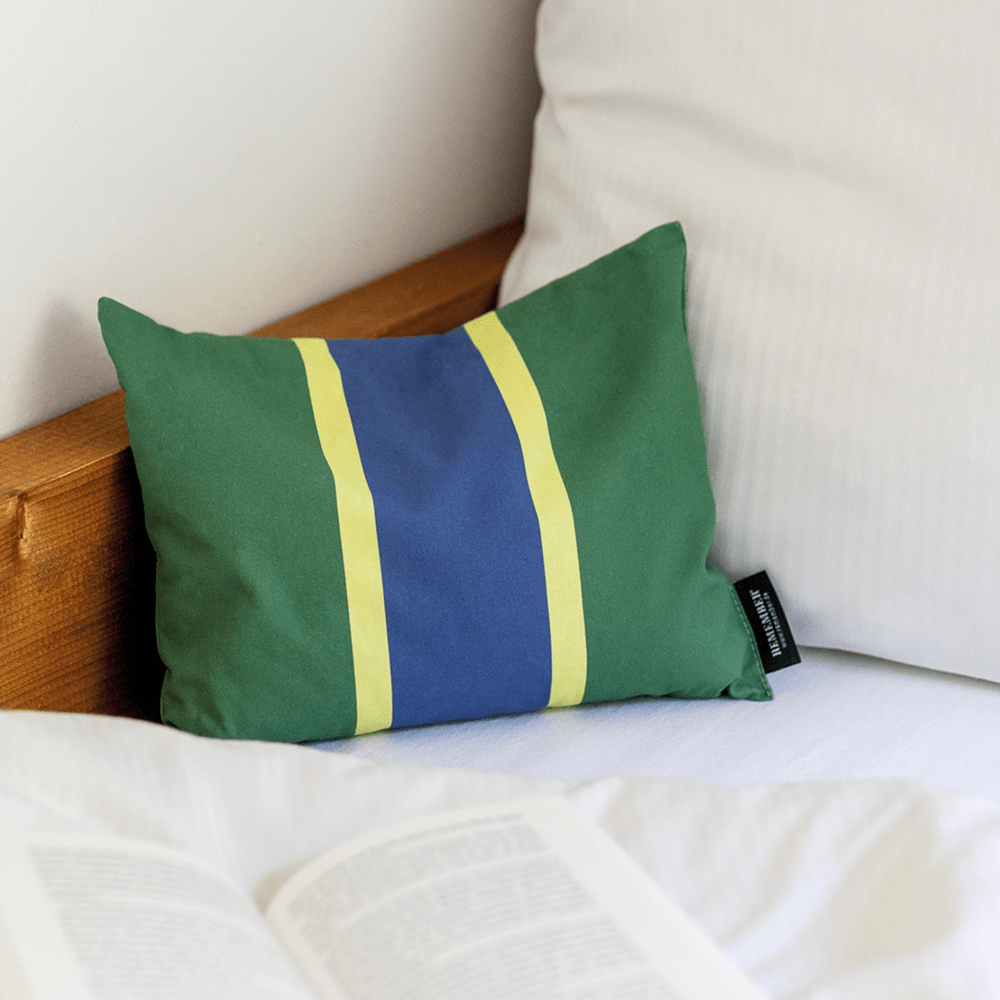 green blue and yellow accent pillow filled with herbs on a bed