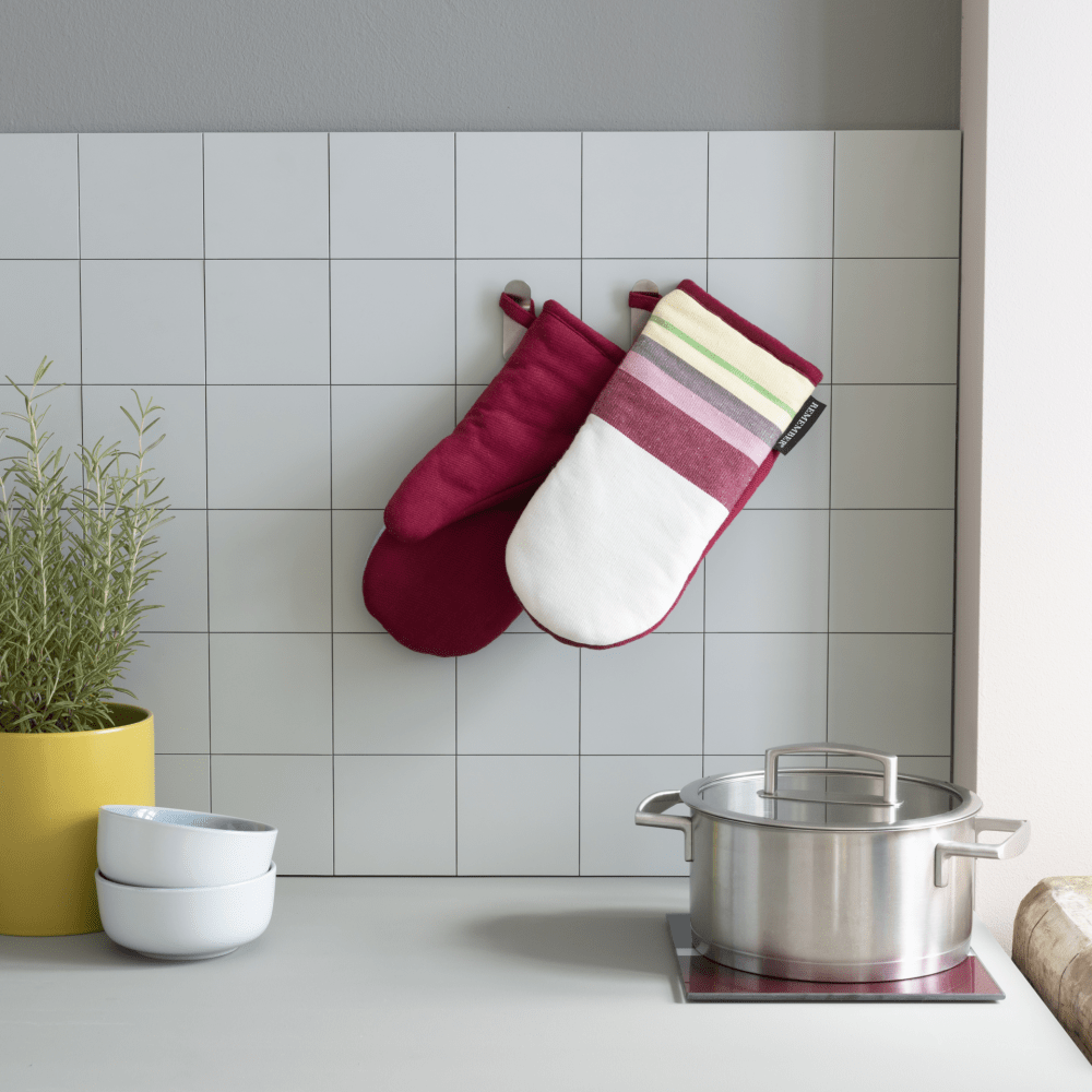 2 color coordinated oven mitts with stripes hanging in kitchen