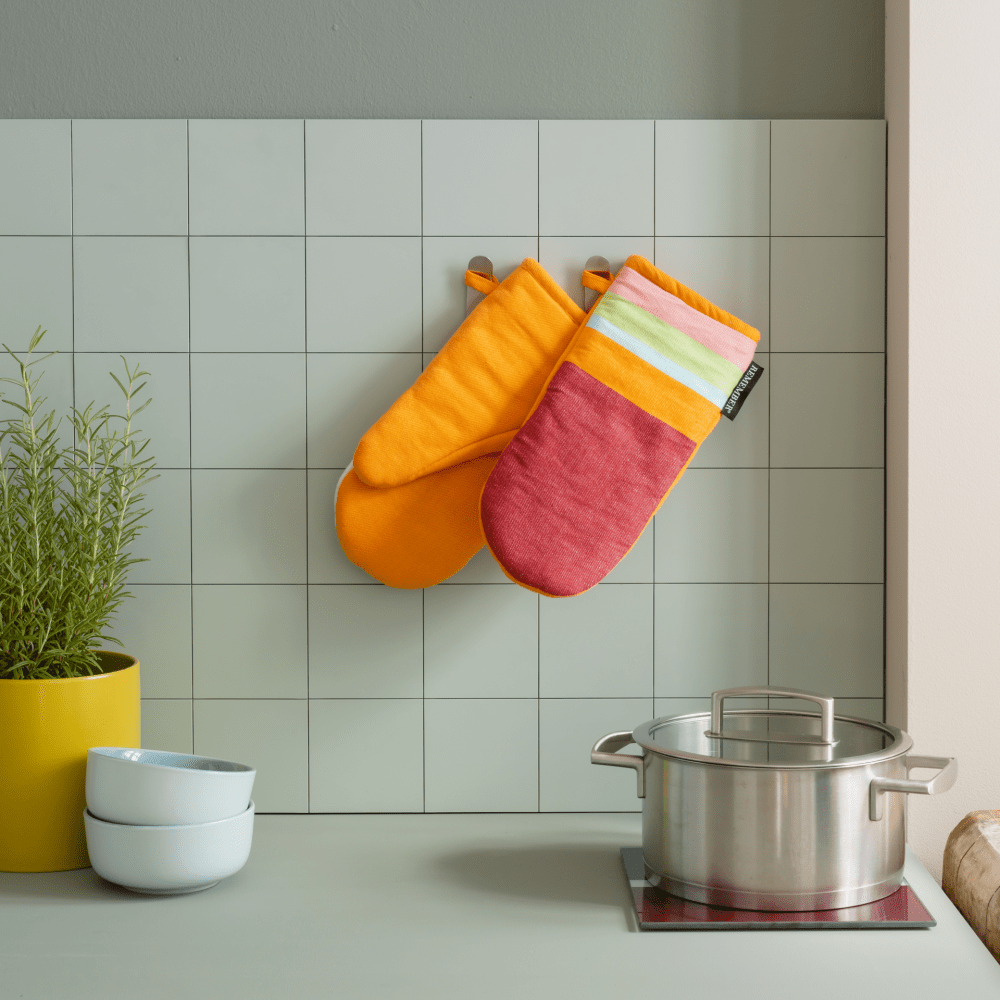 striped oven mitts with orange backing hanging in kitchen