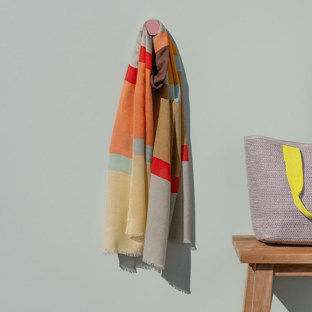 colorful extra long soft scarf hanging on a grey wall with a pink hook