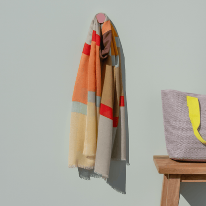 colorful extra long soft scarf hanging on a grey wall with a pink hook
