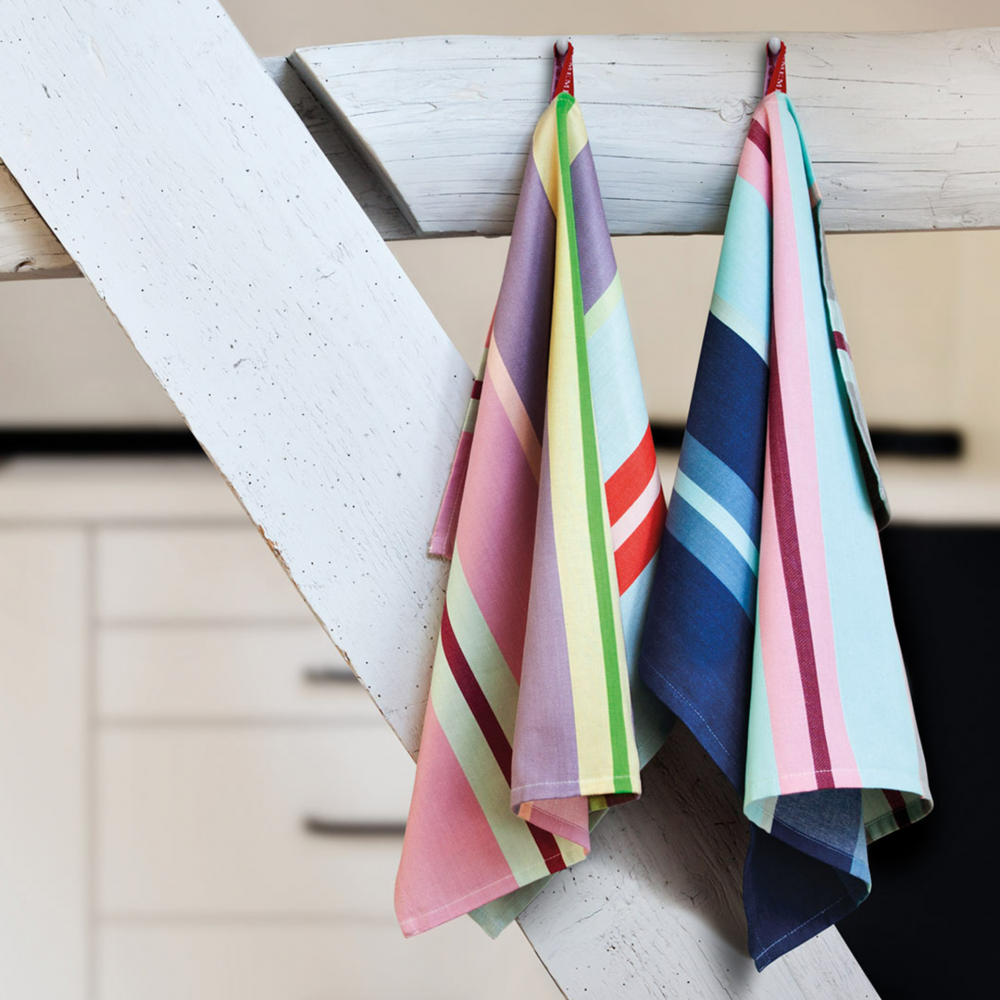 two striped, colorful kitchen towels with big and small stripes hanging in kitchen