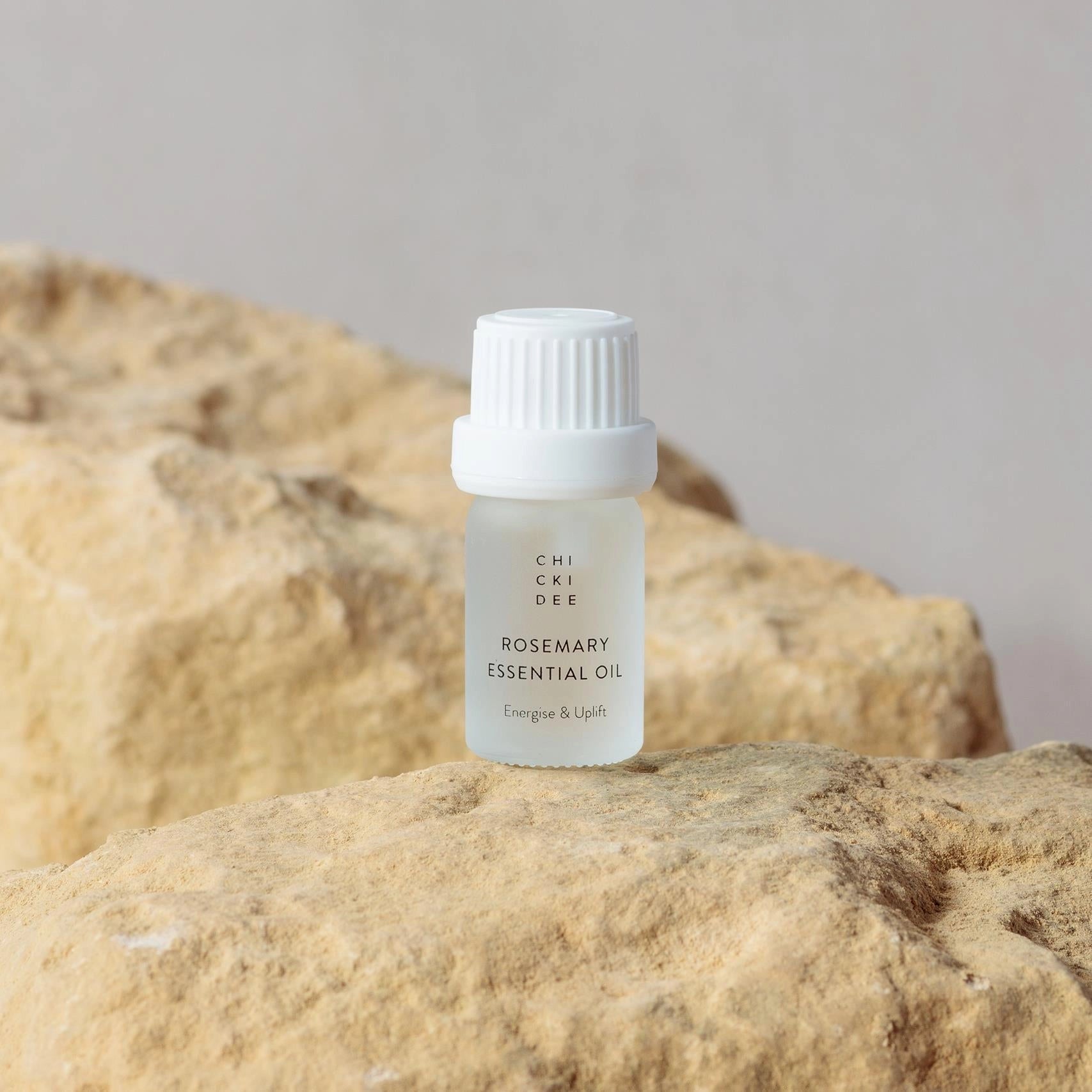 small glass bottle with essential rosemary oil on a rock