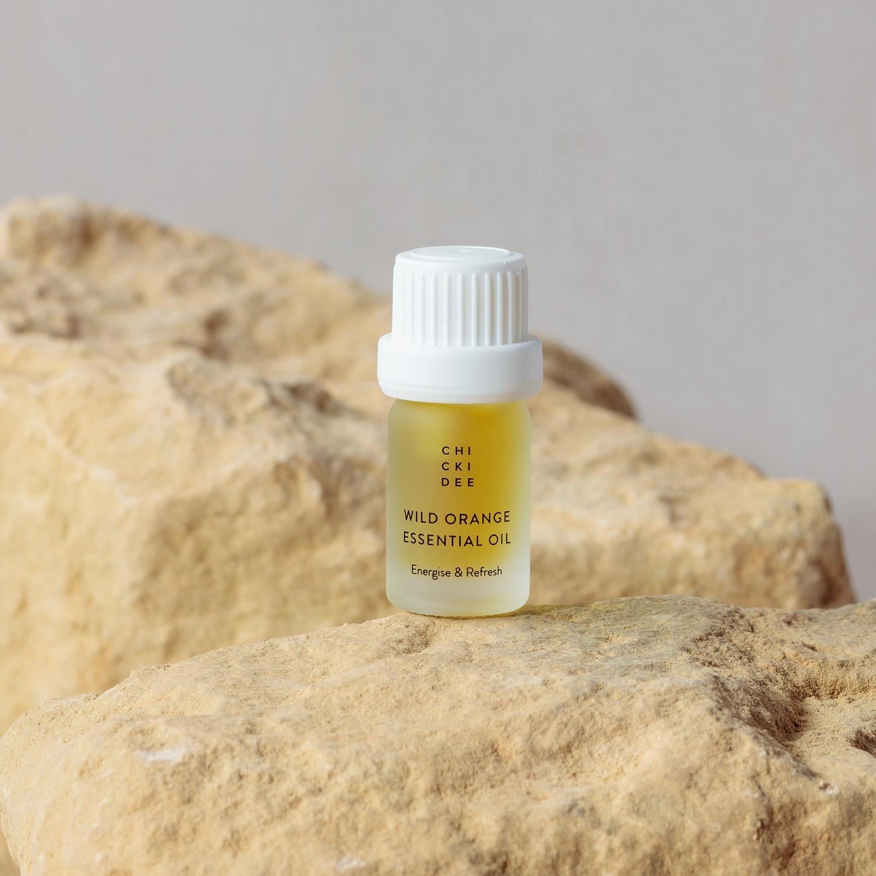 small glass bottle with wild orange essential oil on a rock