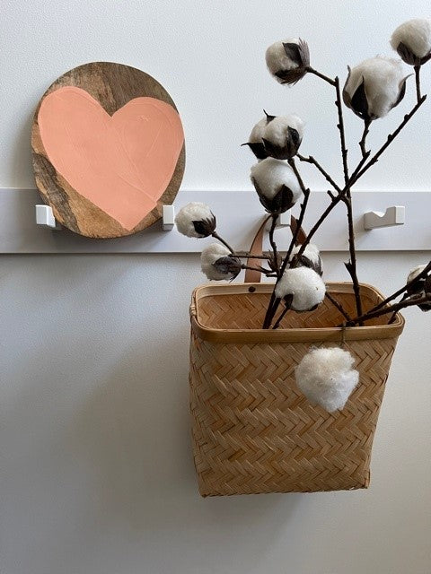 peach colored heart on a natural wooden plate on a rack with a bamboo basket