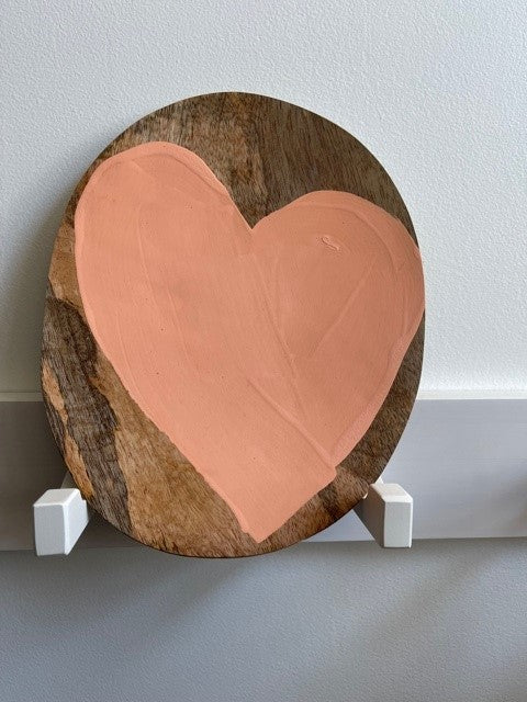 peach colored heart on a natural wooden plate