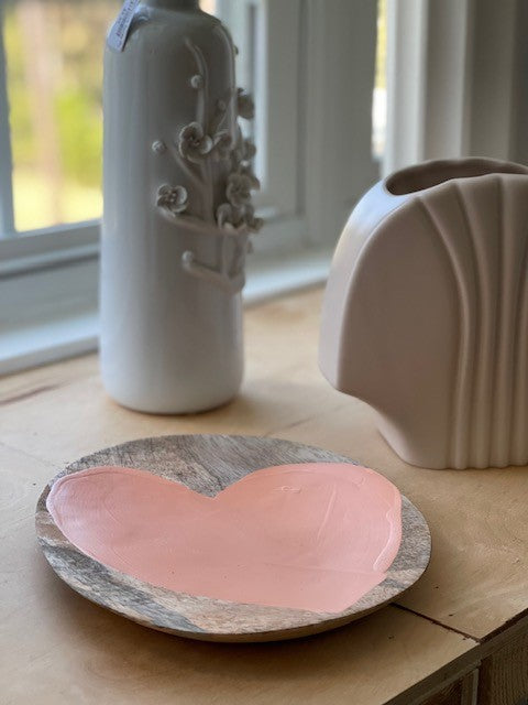 peach heart on a wooden plate next to flower vases