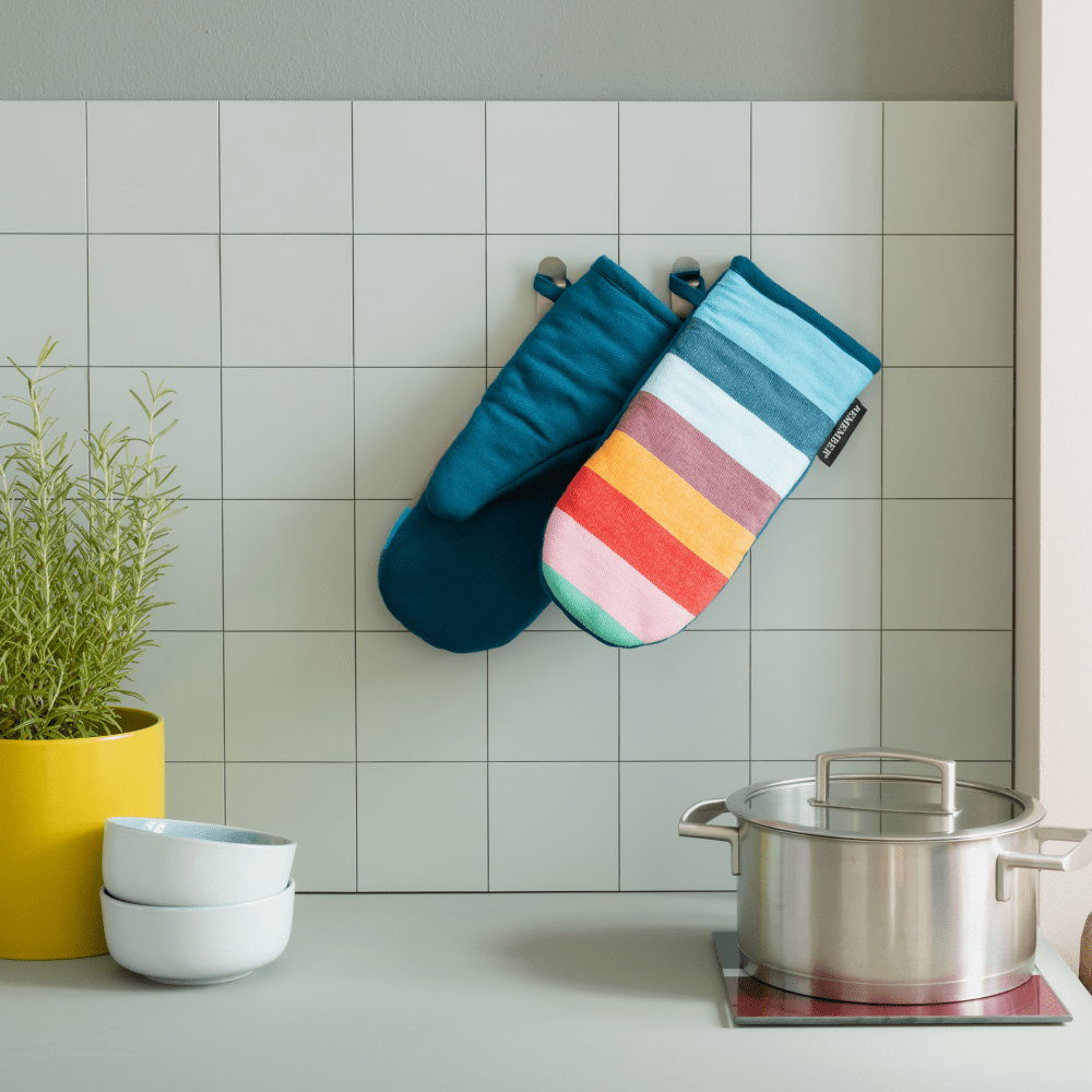 2 striped oven mitts with blue lining hanging in kitchen