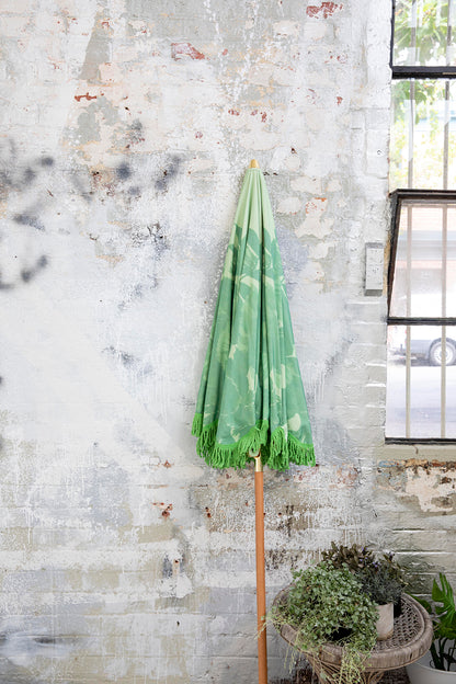 green beach or patio parasol against a grey wall next to a window