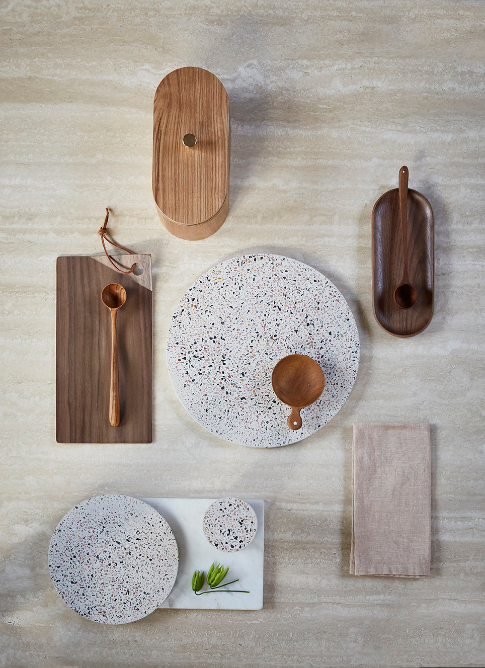marble counter top with round terrazzo cutting plates and a brown wooden oval box with lid
