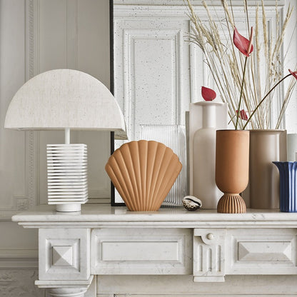 group of vases in white, blue and terracotta orange together on a fire mantel